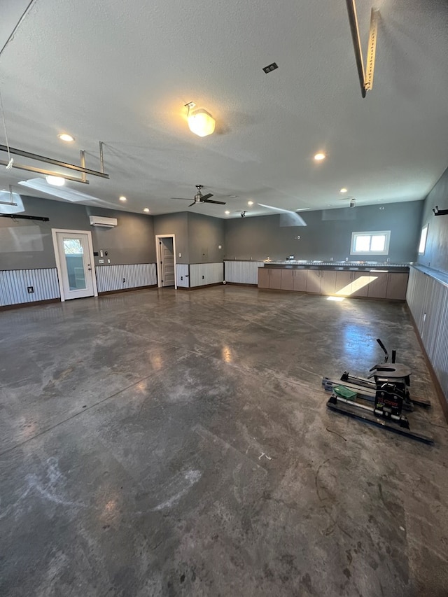 garage with ceiling fan, an AC wall unit, and wainscoting