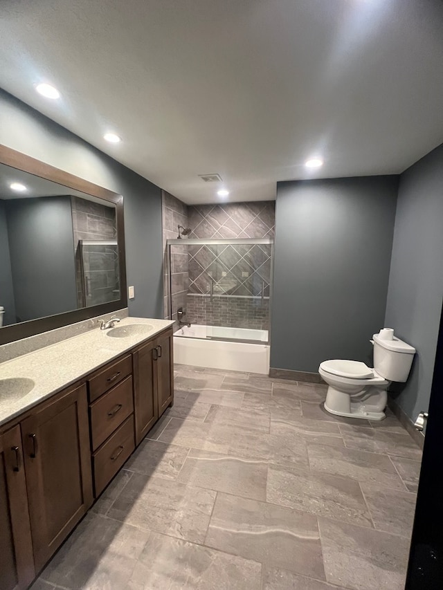 bathroom with tiled shower / bath, double vanity, a sink, and toilet