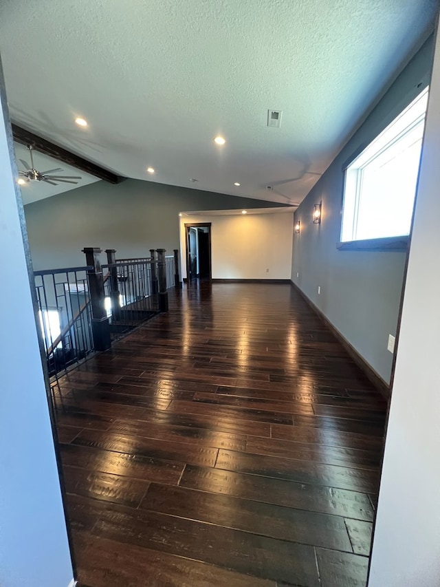 empty room featuring visible vents, vaulted ceiling, a textured ceiling, baseboards, and hardwood / wood-style flooring