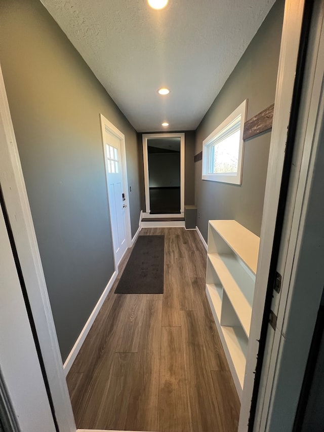 hallway featuring a textured ceiling, baseboards, dark wood-type flooring, and recessed lighting