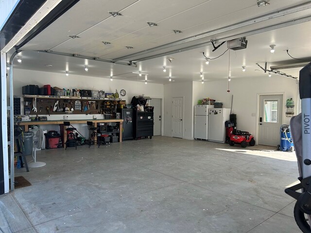 garage featuring a workshop area, white fridge, and a garage door opener