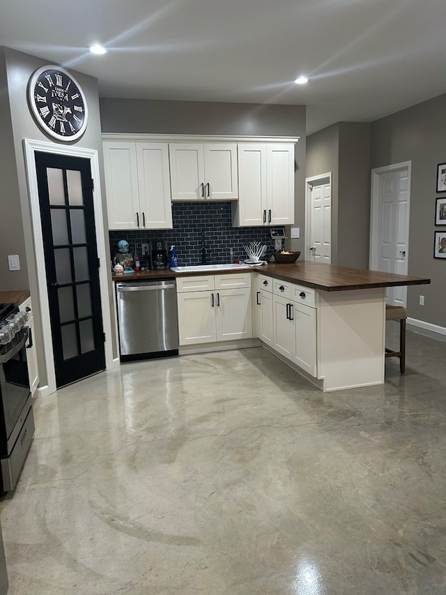 kitchen with a breakfast bar, white cabinets, sink, appliances with stainless steel finishes, and tasteful backsplash