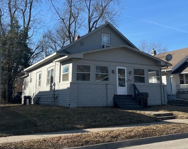 bungalow-style house featuring entry steps, a front lawn, and a chimney