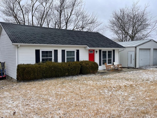 view of front facade with a detached garage and roof with shingles