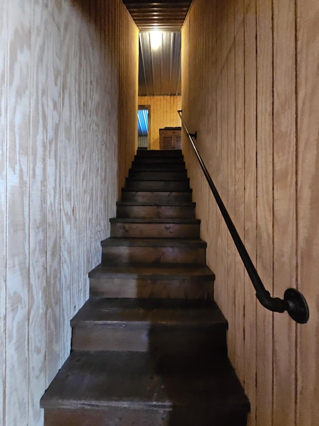 stairs featuring wood walls