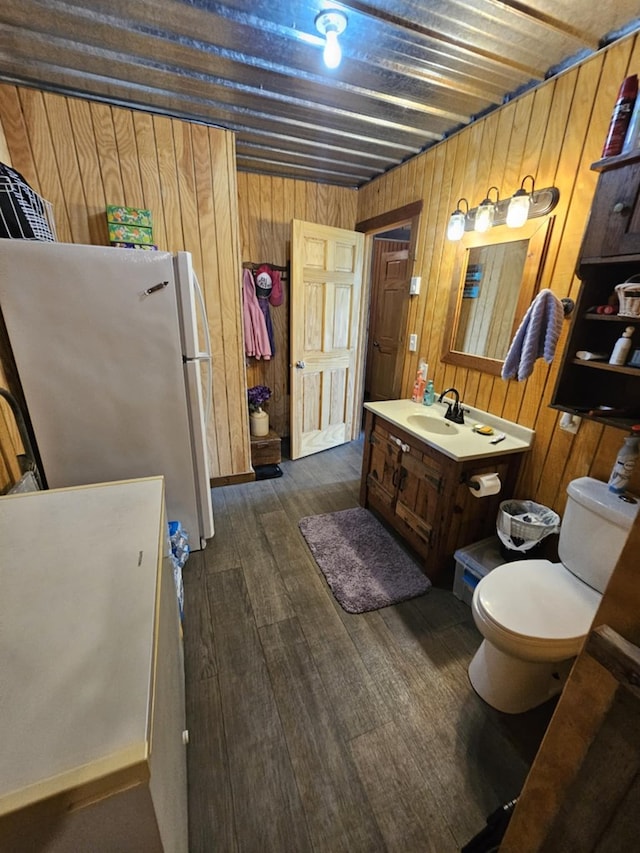 bathroom featuring vanity, hardwood / wood-style floors, toilet, and wood walls