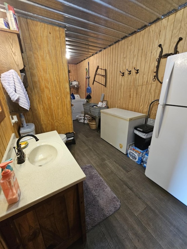 interior space featuring vanity, hardwood / wood-style floors, wooden walls, and washer / clothes dryer