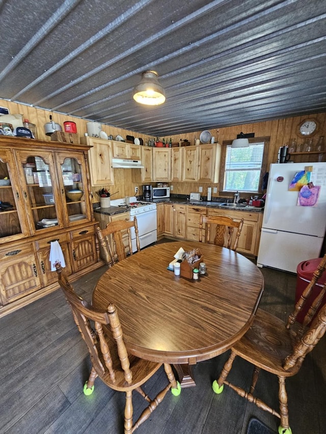 dining area with dark wood-type flooring, sink, and wood walls