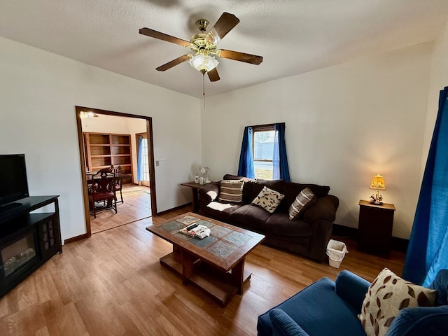 living area with light wood-style floors, ceiling fan, and a textured ceiling