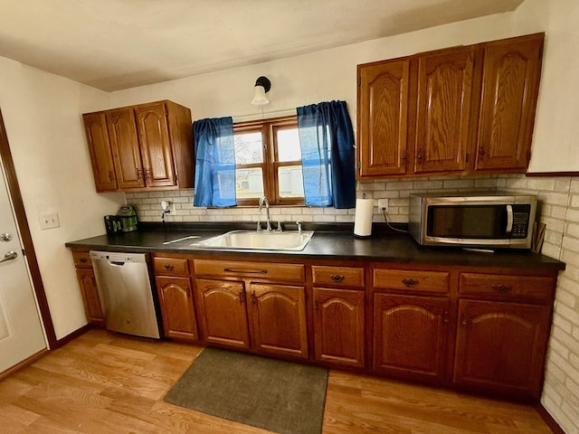 kitchen featuring dark countertops, light wood finished floors, stainless steel appliances, and a sink