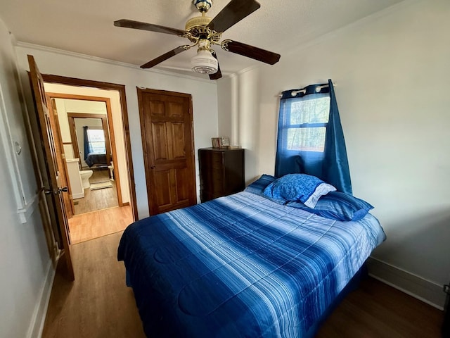 bedroom featuring baseboards, ceiling fan, ornamental molding, wood finished floors, and multiple windows