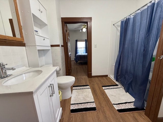 full bathroom featuring tile walls, curtained shower, toilet, vanity, and wood finished floors