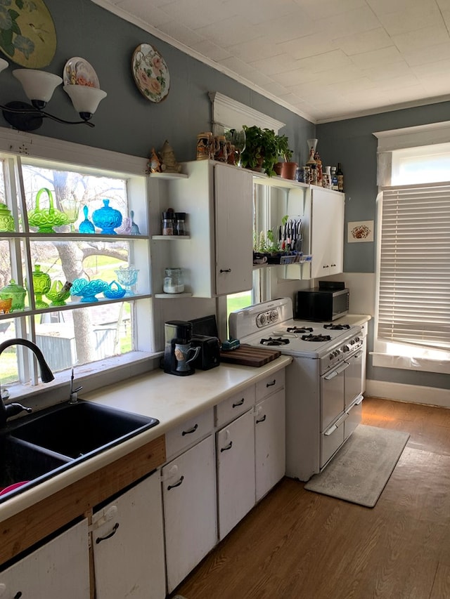 704 N Fourth St, Edina, MO 63537 - kitchen with white range with gas stovetop, stainless steel microwave, white cabinetry, a sink, and open shelves
