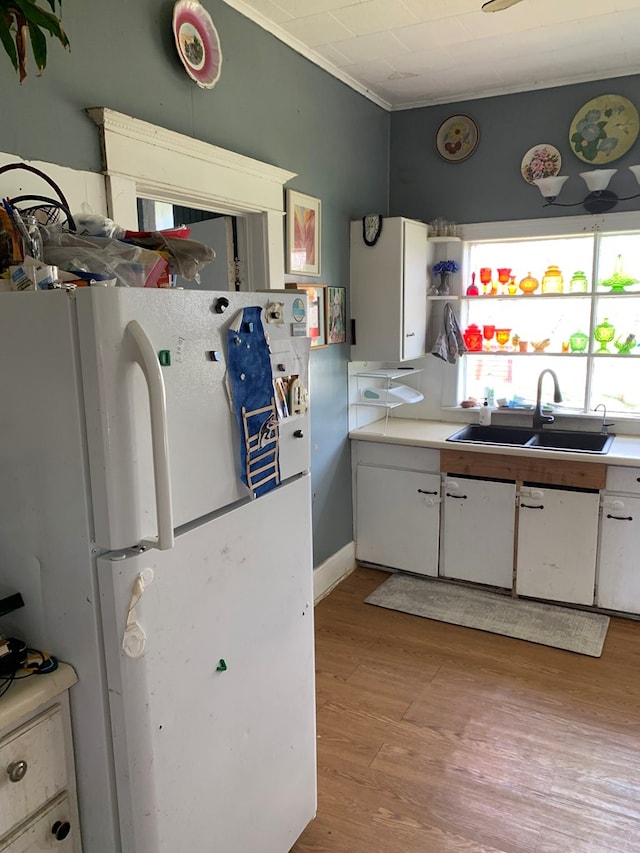 704 N Fourth St, Edina, MO 63537 - kitchen with light countertops, light wood-type flooring, a sink, freestanding refrigerator, and white cabinets