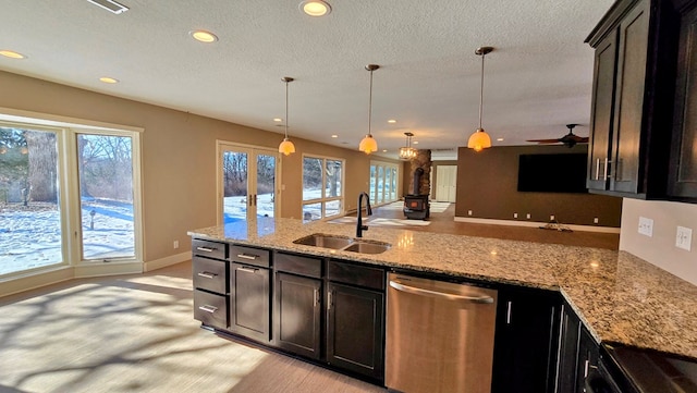 kitchen with ceiling fan, dishwasher, sink, light stone counters, and pendant lighting