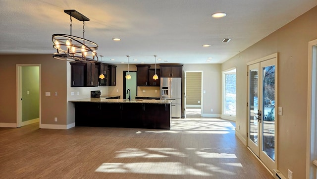 kitchen featuring dark brown cabinetry, an inviting chandelier, stainless steel refrigerator with ice dispenser, kitchen peninsula, and pendant lighting