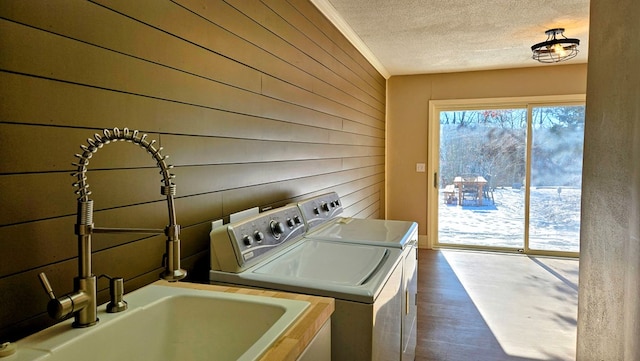 laundry area with hardwood / wood-style floors, a textured ceiling, washer and clothes dryer, and wooden walls