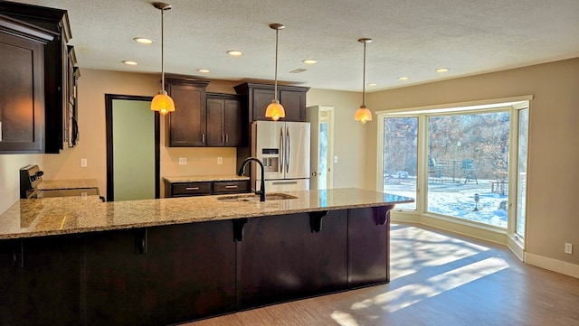 kitchen with decorative light fixtures, stainless steel appliances, light stone counters, and sink