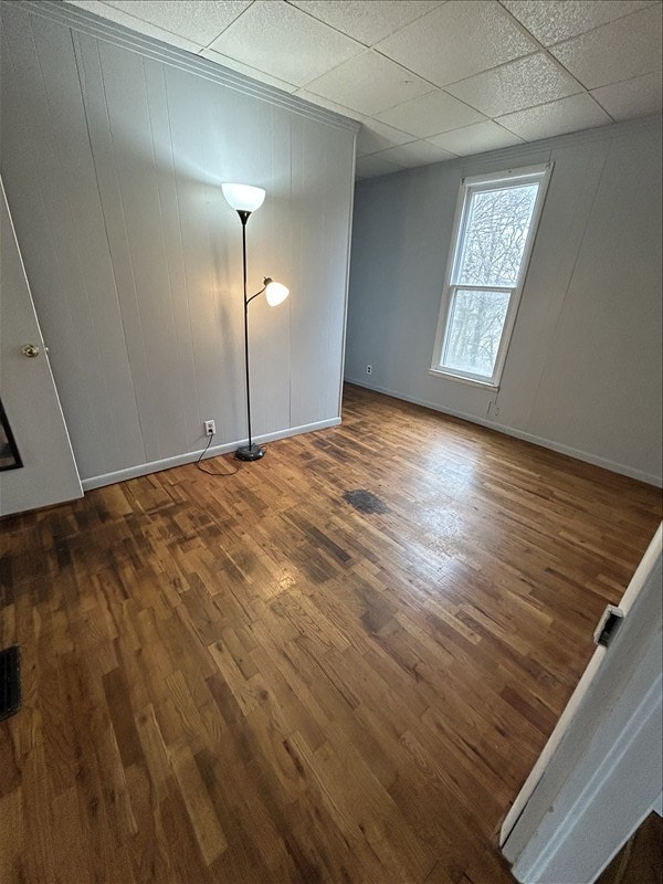 spare room featuring dark hardwood / wood-style floors and a drop ceiling