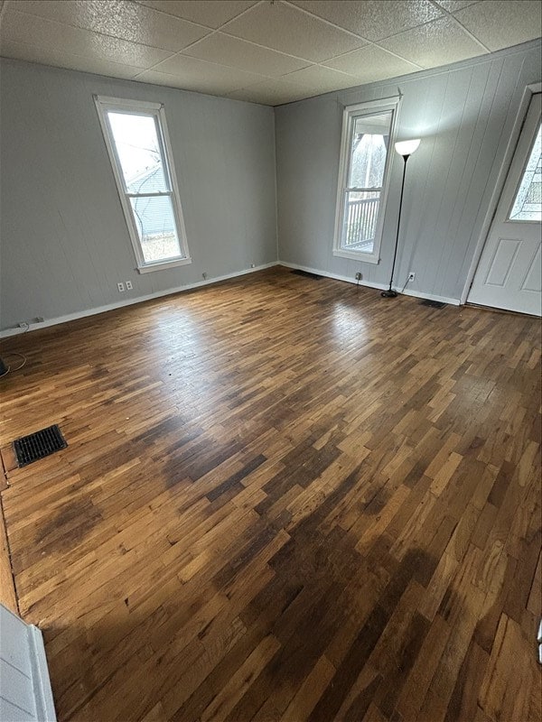 empty room with a drop ceiling and dark wood-type flooring