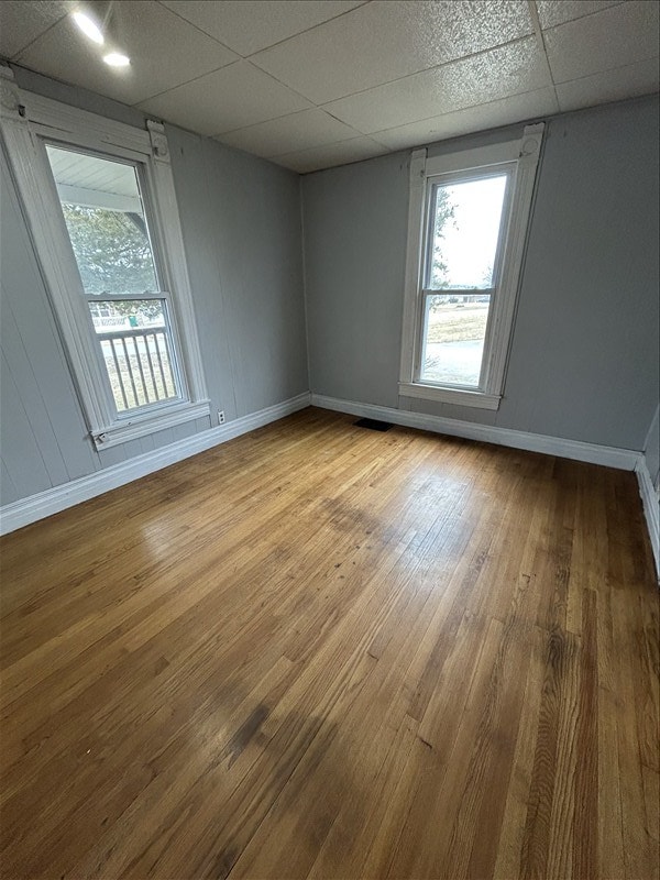 spare room featuring a drop ceiling and wood-type flooring