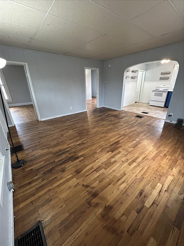 unfurnished living room with dark hardwood / wood-style floors and a drop ceiling