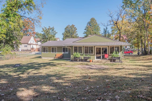 rear view of property featuring a sunroom and a yard