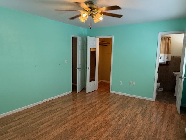 unfurnished bedroom featuring hardwood / wood-style floors, ceiling fan, and ensuite bathroom