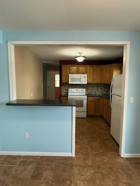 kitchen featuring white appliances, kitchen peninsula, and decorative backsplash