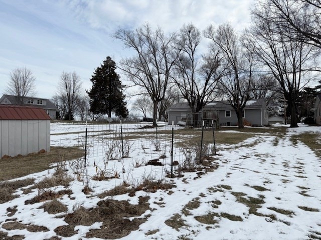 snowy yard with a storage shed