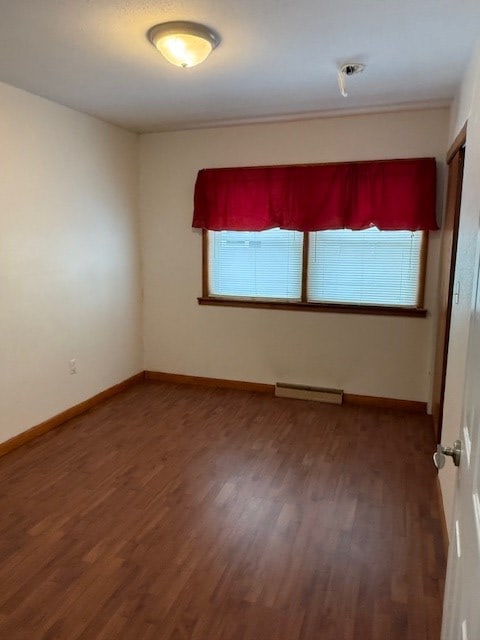 empty room featuring dark hardwood / wood-style flooring and baseboard heating