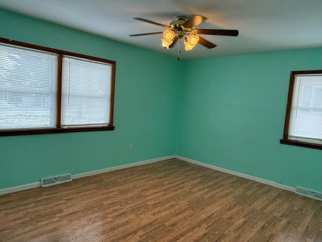 empty room with dark wood-type flooring and ceiling fan