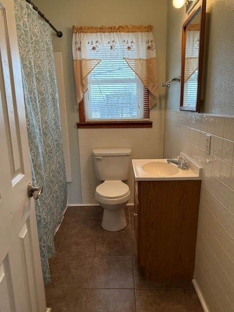 bathroom with vanity, toilet, curtained shower, and tile walls