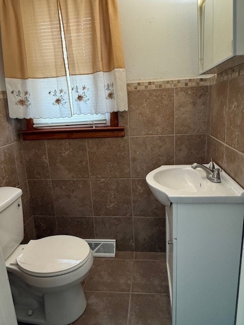 bathroom with tile patterned flooring, vanity, tile walls, and toilet