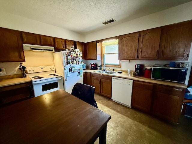 kitchen featuring white appliances, ventilation hood, visible vents, a sink, and a textured ceiling