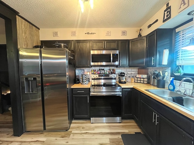 kitchen featuring stainless steel appliances, tasteful backsplash, butcher block counters, and sink