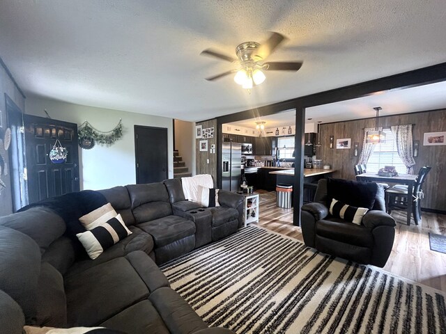 639 Missouri Ave, Chillicothe, MO 64601 - living area with wooden walls, light wood finished floors, a ceiling fan, a textured ceiling, and stairway