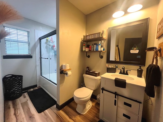 full bathroom featuring toilet, vanity, enclosed tub / shower combo, and hardwood / wood-style flooring