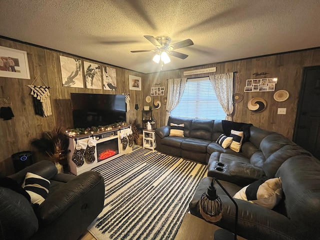 living room with ceiling fan, wood walls, and a textured ceiling