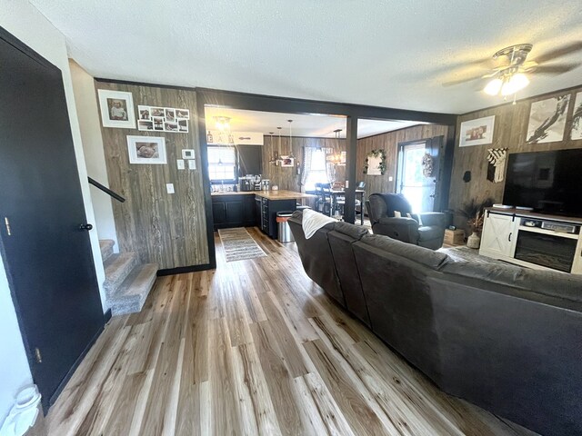 639 Missouri Ave, Chillicothe, MO 64601 - living area featuring wood walls, light wood-style flooring, stairs, plenty of natural light, and a ceiling fan