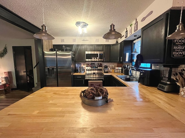 kitchen with sink, hanging light fixtures, a textured ceiling, kitchen peninsula, and stainless steel appliances