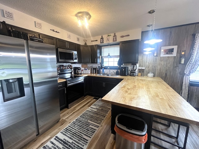 639 Missouri Ave, Chillicothe, MO 64601 - kitchen with appliances with stainless steel finishes, light wood-style flooring, a peninsula, backsplash, and a textured ceiling