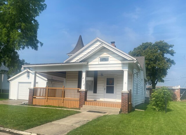 418 Elm St, Chillicothe, MO 64601 - view of front of house featuring covered porch, a front yard, an outbuilding, and an attached garage
