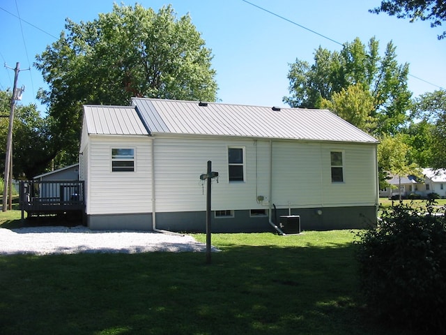 rear view of house featuring a deck, a yard, and central AC