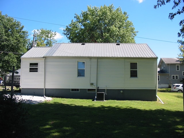 rear view of property featuring a lawn and cooling unit