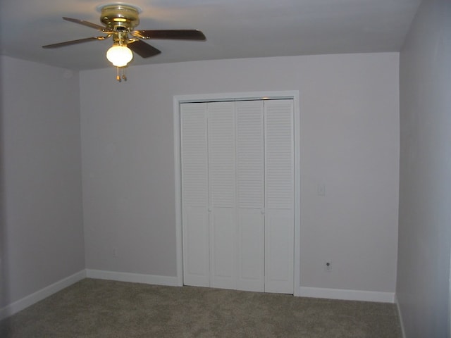 unfurnished bedroom featuring dark colored carpet, a closet, and ceiling fan