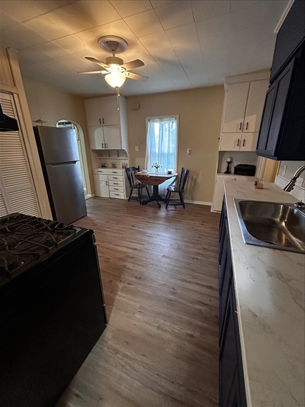 1617 N Church St, Marceline, MO 64658 - kitchen featuring black gas range, white cabinetry, light countertops, a ceiling fan, and dark wood-type flooring