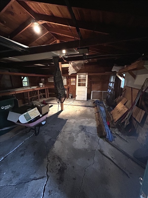 1617 N Church St, Marceline, MO 64658 - misc room featuring a garage, unfinished concrete floors, vaulted ceiling, and wood walls