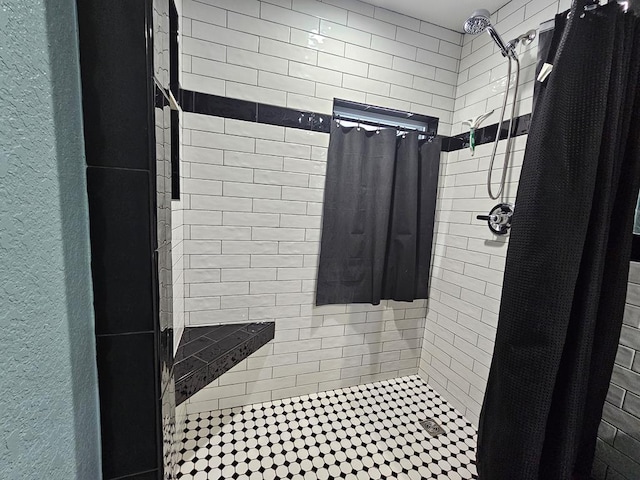 bathroom with tiled shower and a textured wall