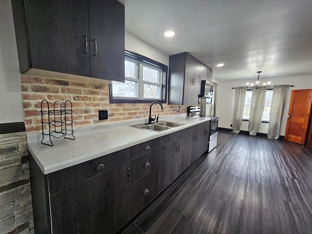 kitchen with stainless steel microwave, dark wood-style flooring, an inviting chandelier, a sink, and range with electric cooktop